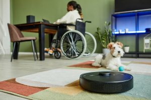 Robot vacuum in smart home with woman in wheelchair at desk and dog on rug