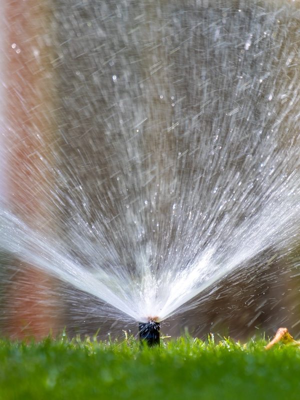 Close-up of a smart irrigation watering a lawn.